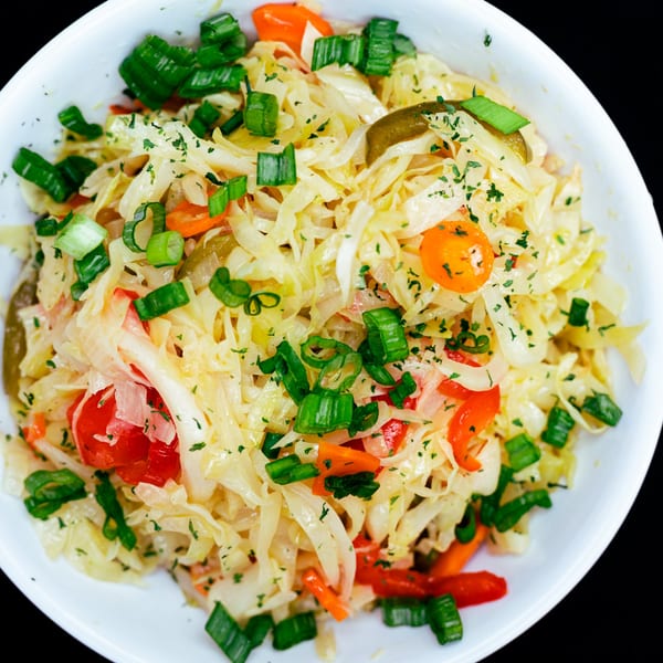 Close-up of Caribbean coleslaw with shredded cabbage, red peppers, carrots, and green onions.